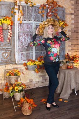 Bir şekilde dekore edilmiş evde duran sonbahar kadın. Arka planda, sonbahar natürmort düşmek. Bir çelenk başında sarı solmuş yaprakların giyen kız. Altın çiçek ve bırakın