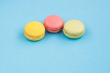 Mavi arka plan üzerinde macaroons, pembe, sarı ve yeşil macaroons