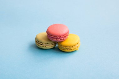Mavi arka plan üzerinde renkli macaroons, pembe, sarı ve yeşil macaroons. Tatlılar, tatlılar. Copyplace, metin için yer. 