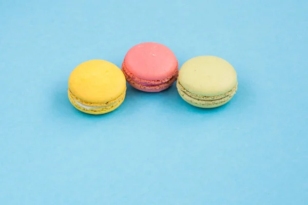 Macaroons, pink, yellow and green macaroons on blue background