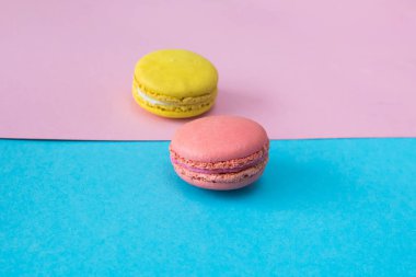 Mavi ve pembe arka plan üzerinde pembe macaron, yakın çekim. Sarı macaron arka plan üzerinde. Seçici odak