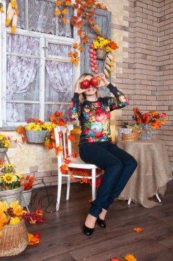 Gülümseyen ve kırmızı elma evde Sonbahar dekorasyonu ile oynarken mutlu kadın. Mutlu kadının sonbahar. 