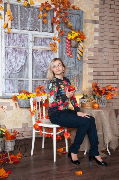 Kırmızı elma sonbahar kadınla. Süslü sonbahar evde oturan bir genç bayan. Altın çiçek ve yaprakları. Mutlu kadının sonbahar. 