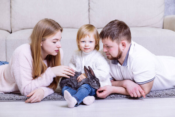 Счастливая семья играет с кроликом на хоме