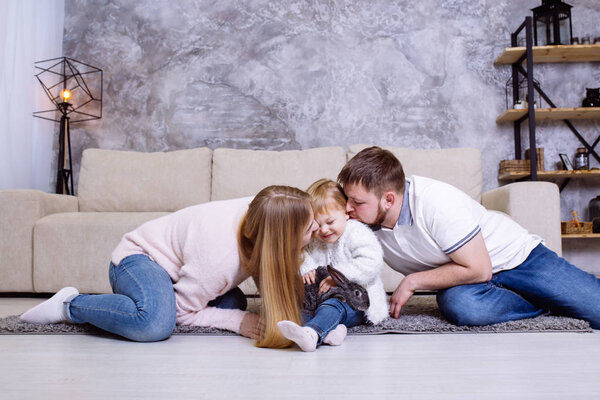 Родители целуют ее дочь. Счастливая семья, весело проводящая время на хоме