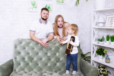 Genç aile evde birlikte eğleniyor. Anne, baba ve kız tahta tren, oyuncak lokomotifle oynuyorlar.