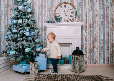 Noel ağacının yanında iskambil mutlu çocuk. Şömine ve Noel ağacı yanında küçük çocuk evde