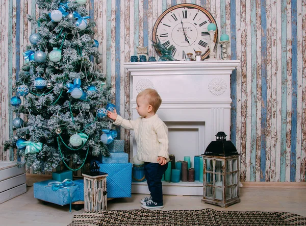 白いニットのセーター立っているクリスマス ツリーの近くで小さい男の子 — ストック写真