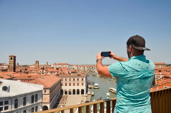 Tourist man travel in Italy, Venice. View on Grand canal. Man making photo using his smartphone standing and looking on roof top. Man tourist travel in Italy. Copyspace