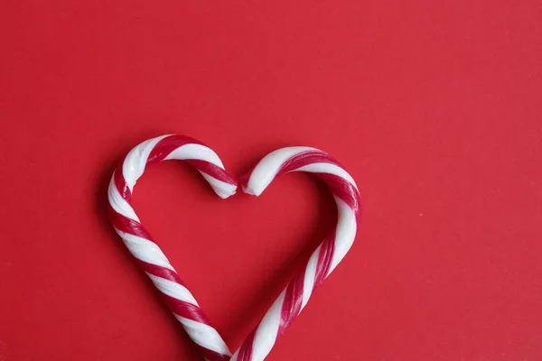Two candy canes making a heart on a red background, Candy cane heart.  Love concept. Copyplace, space for text and logo.