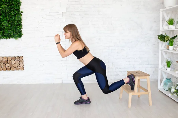 Sportive woman wearing black leggings and top sitting on chair Stock Photo