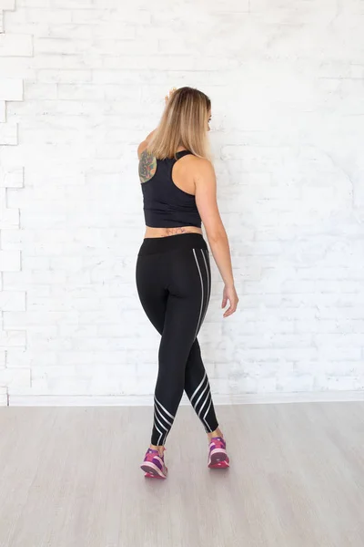 Sexy woman with tattoo in black leggings and top. Sportive woman