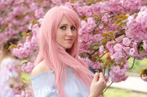 Schöne Frau mit rosa Haaren im blühenden Garten — Stockfoto