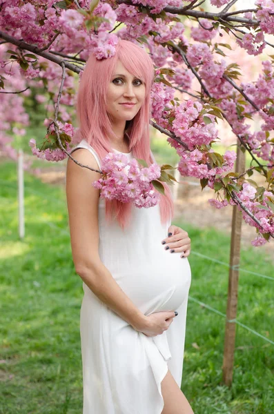 Piękna kobieta w ciąży z rękami nad brzuch w sukni z — Zdjęcie stockowe