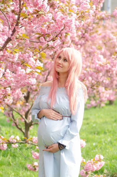 Gravid kvinna med blommande träd på bakgrunden. Moderskapet, pre — Stockfoto