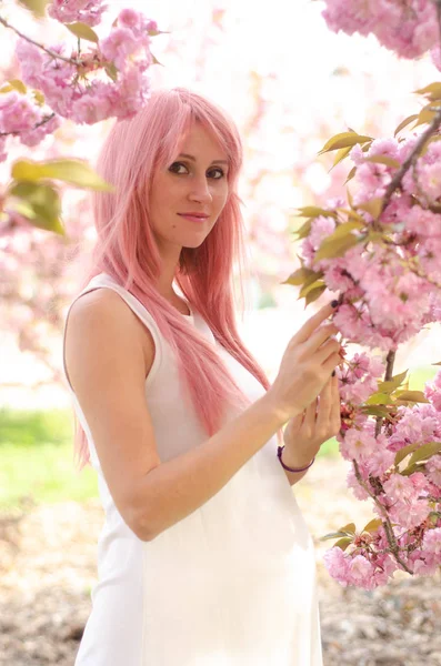 Schöne schwangere Frau in der Nähe von rosa Sakura blühenden Baum — Stockfoto