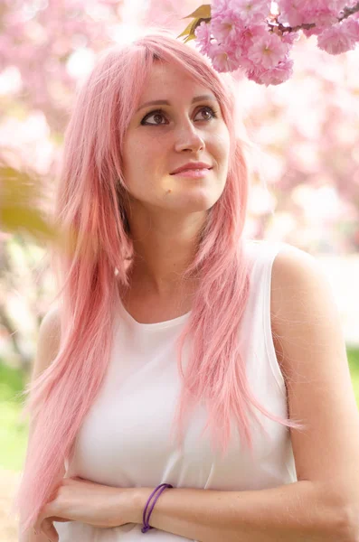 Mulher bonita perto de árvore florescendo sakura. Menina com cabelo rosa o — Fotografia de Stock