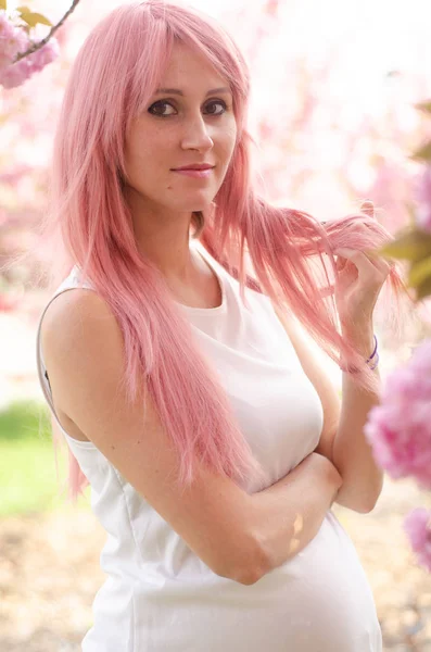 Kobieta w pobliżu kwitnącego drzewa Sakura. Dziewczyna z różowymi włosami na kwitnącym — Zdjęcie stockowe