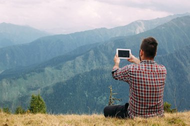 Gürcistan'ın Svaneti'ndeki dağda tabletiyle fotoğraf yapan adam