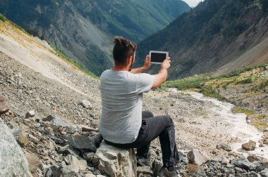 Adam yürüyüşçü Svaneti dağda onun tablet ile fotoğraf yapma