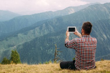 Adam yürüyüşçü Svaneti dağda onun tablet ile fotoğraf yapma