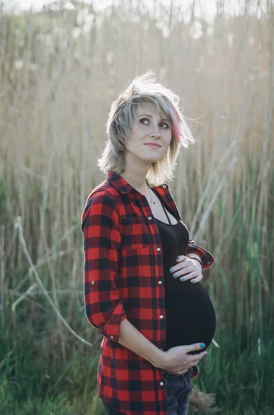 Красивая беременная женщина в парке на закате — стоковое фото