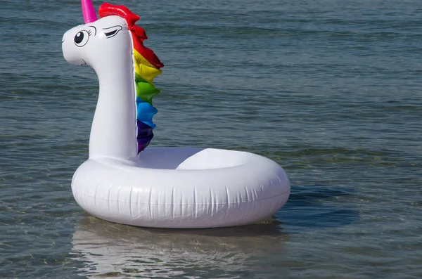 Inflatable unicorn pool toy on sea background. Minimal summer co