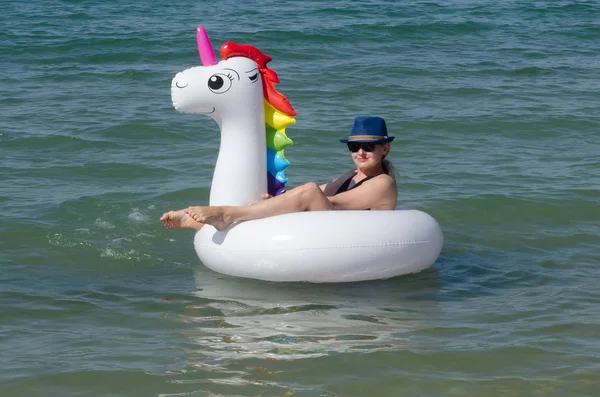 Woman on unicorn inflatable tube float on the sea
