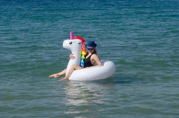 Mujer relajándose en la piscina inflable unicornio flotar cerca del mar — Foto de Stock