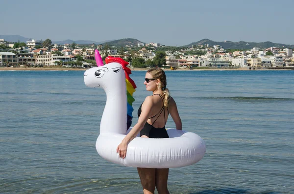Mujer con flotador de piscina inflable unicornio de pie cerca de Mediterra — Foto de Stock