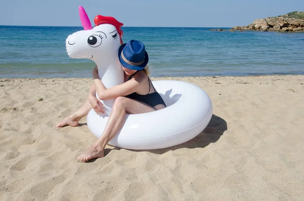 Mujer con unicornio inflable sobre arena cerca del mar . — Foto de Stock
