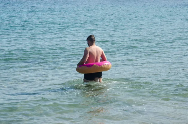Hombre con anillo de rosquilla inflable nadando en el mar Mediterráneo — Foto de Stock