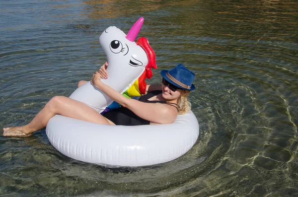 Woman with inflatable unicorn pool float floating in Mediterrane
