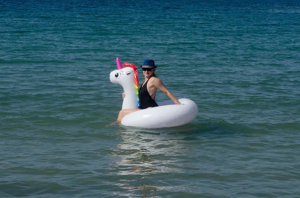 Mujer de moda joven relajándose con tubo de unicornio inflable en el mar — Foto de Stock