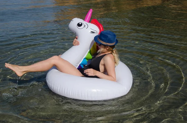 Joven mujer feliz flotando en la piscina de unicornio inflable flotar en s — Foto de Stock