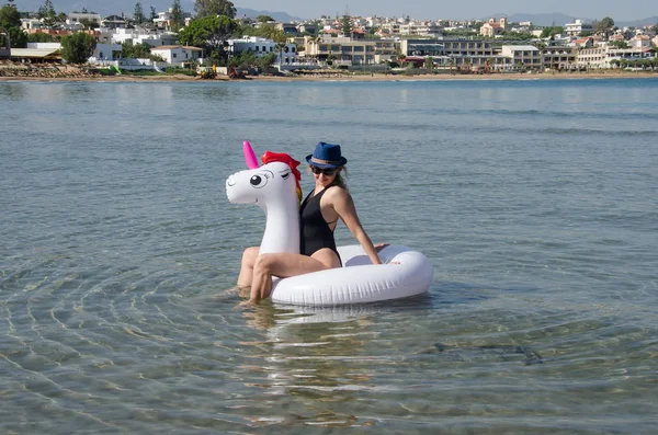 Mujer relajándose en flotador de unicornio inflable cerca del mar con Chania — Foto de Stock