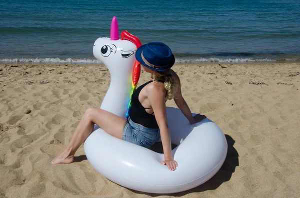 Verano y vacaciones. Mujer joven sentada en unicornio inflable p — Foto de Stock