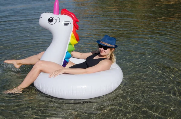 Woman with inflatable unicorn pool float swimming in Mediterrane