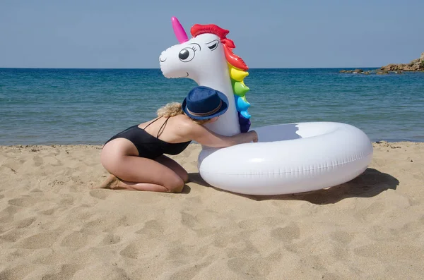 Woman with inflatable unicorn pool float near sea on beach