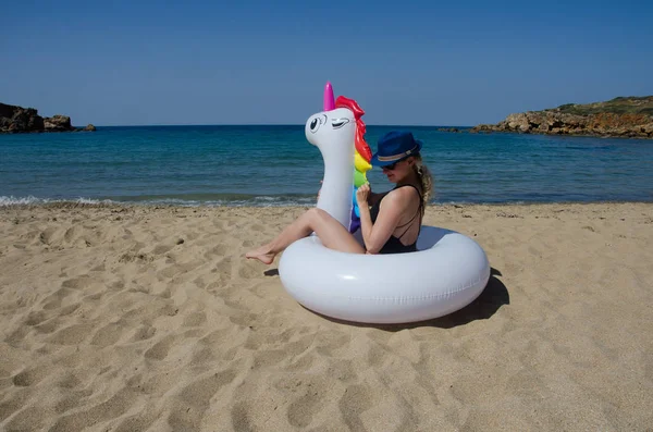 Mujer de moda joven relajándose con unicornio inflable en la playa — Foto de Stock