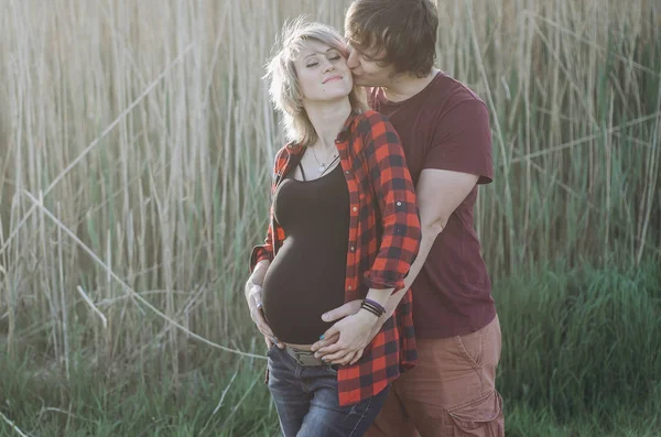 Gravid kvinna och hennes man kramar på magen tillsammans i — Stockfoto