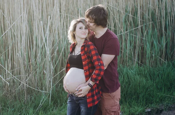 Gravid kvinna och hennes kärleksfulla man poserar vid solnedgången — Stockfoto