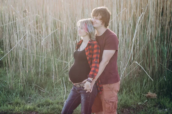 Gravid kvinna och man poserar vid solnedgången i naturen — Stockfoto