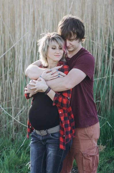 Smiling pregnant young couple hugging while standing together at — Stock Photo, Image