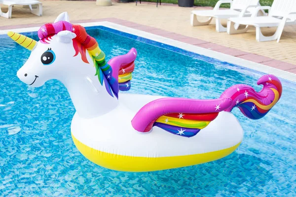 Unicorn inflatable float. Unicorn pool float in blue water backg