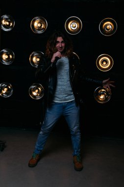 erkek şarkıcı parlak fenerler, çerçevede uzun saçlı sahne alanı üzerinde mikrofon ile sahne