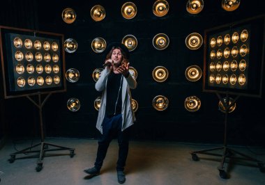 erkek şarkıcı parlak fenerler, çerçevede uzun saçlı sahne alanı üzerinde mikrofon ile sahne