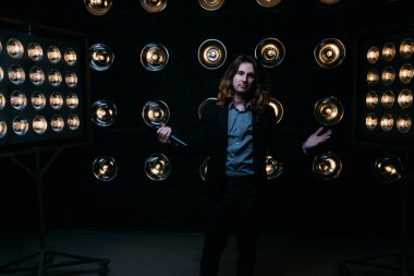 Parlak fenerler, çerçevede uzun saçlı sahne alanı üzerinde mikrofon ile acımasız şarkıcı sahne