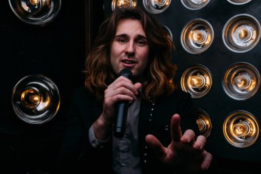 Parlak fenerler, çerçevede uzun saçlı sahne alanı üzerinde mikrofon ile acımasız şarkıcı sahne