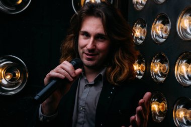 Parlak fenerler, çerçevede uzun saçlı sahne alanı üzerinde mikrofon ile acımasız şarkıcı sahne